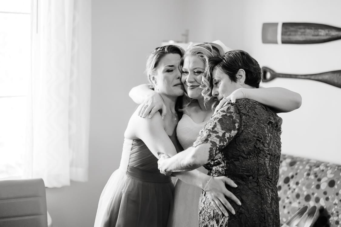 Mother and sister hug bride after she is done getting ready
