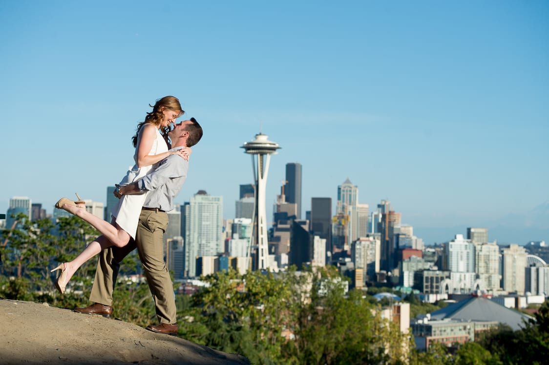 Iconic engagement picture of guy picking up his fiancé with Seattle as a backdrop at Kerry Park in Seattle