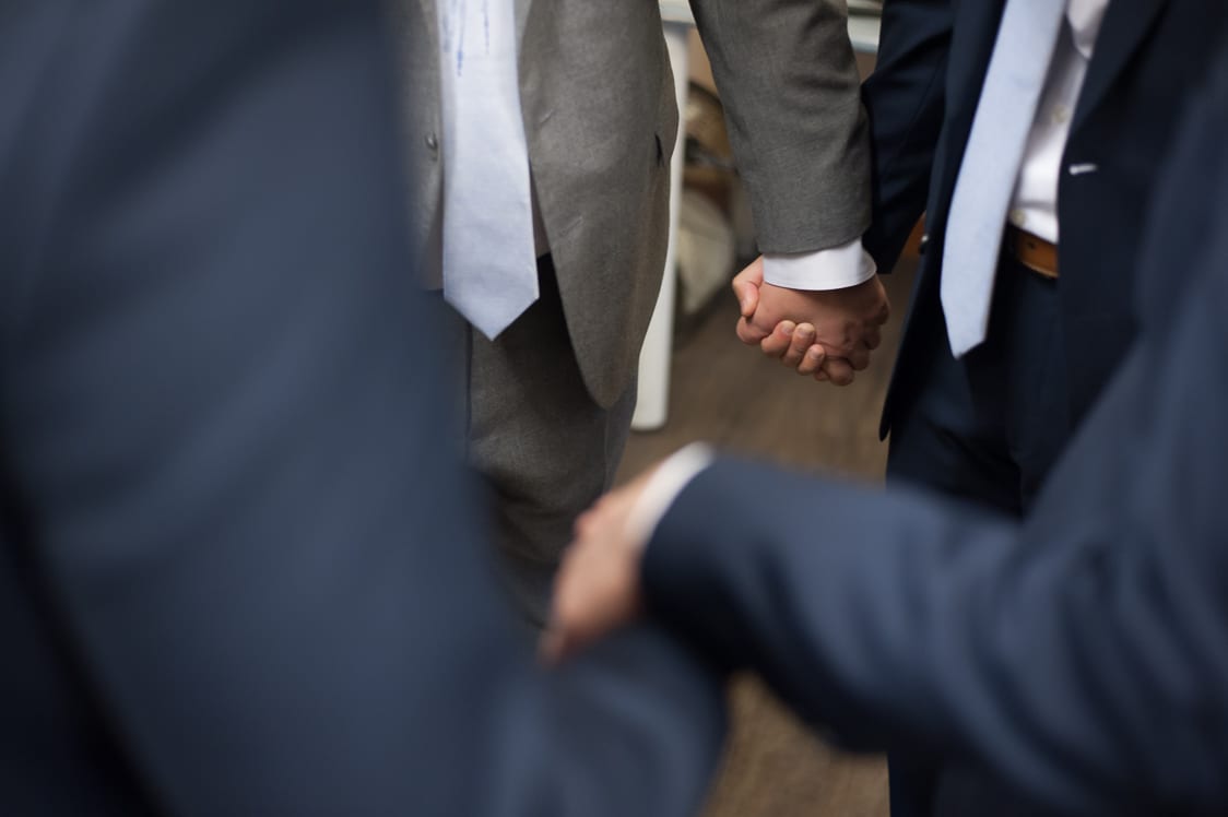 Guys holding hands while praying before the wedding at the Pickering Barn in Issaquah, WA