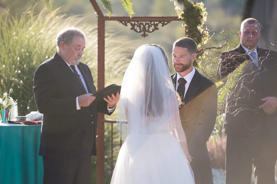 Groom looks at bride during wedding ceremony at Selene Homestead