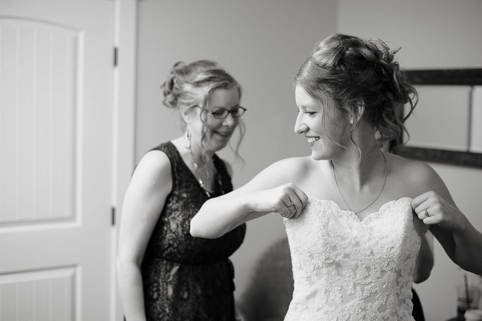 Mother helps her daughter get into her wedding dress at Evergreen Gardens wedding venue