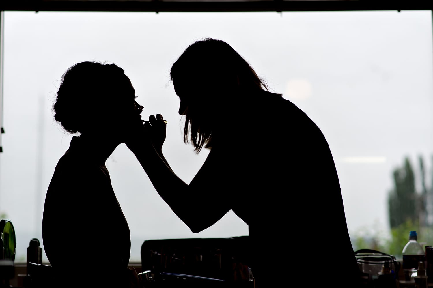 silhouette of bride getting her makeup done at Maplehurst Farm wedding venue